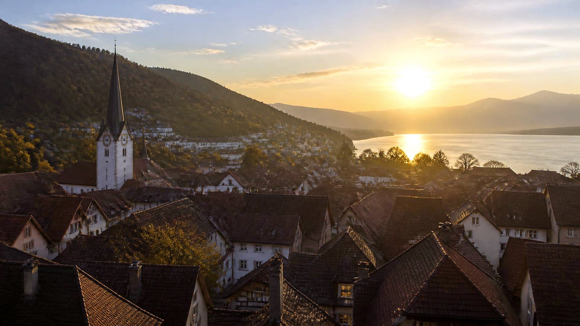 Senamiesčio stogai ir bažnyčios bokštas auksinėje vakaro šviesoje